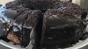 Um bolo de chocolate com granulado sobre um suporte branco.