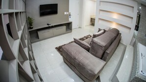 A modern living room with a sofa, TV, and built-in shelves. - Hotel HPR Executive (Vitorino)