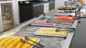 A buffet line with various food items including fruits, meats, and pasta. - Hotel HPR Executive (Vitorino)