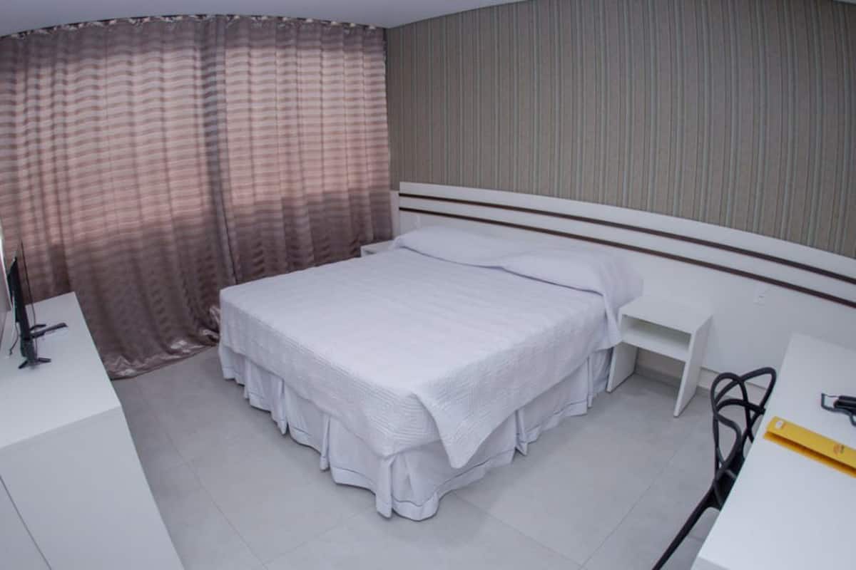 Un dormitorio con una cama, un escritorio y una silla.
