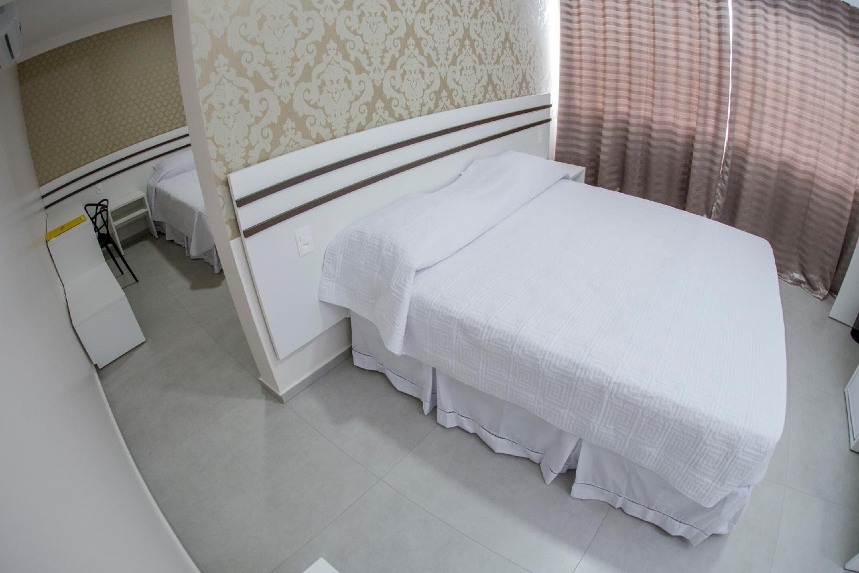 A neatly arranged hotel room with a bed, a small desk, and a chair.