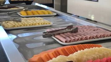 A buffet with various food items including fruits and pastries.