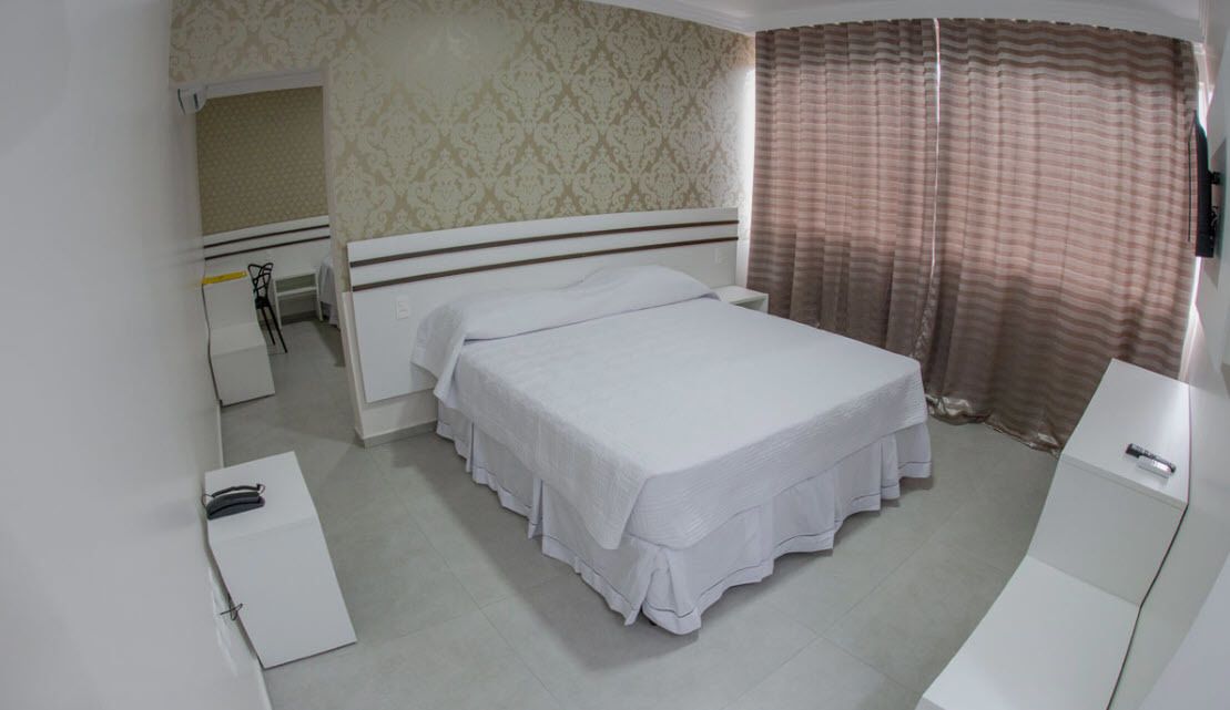 A bedroom with a bed, a desk, and a chair.