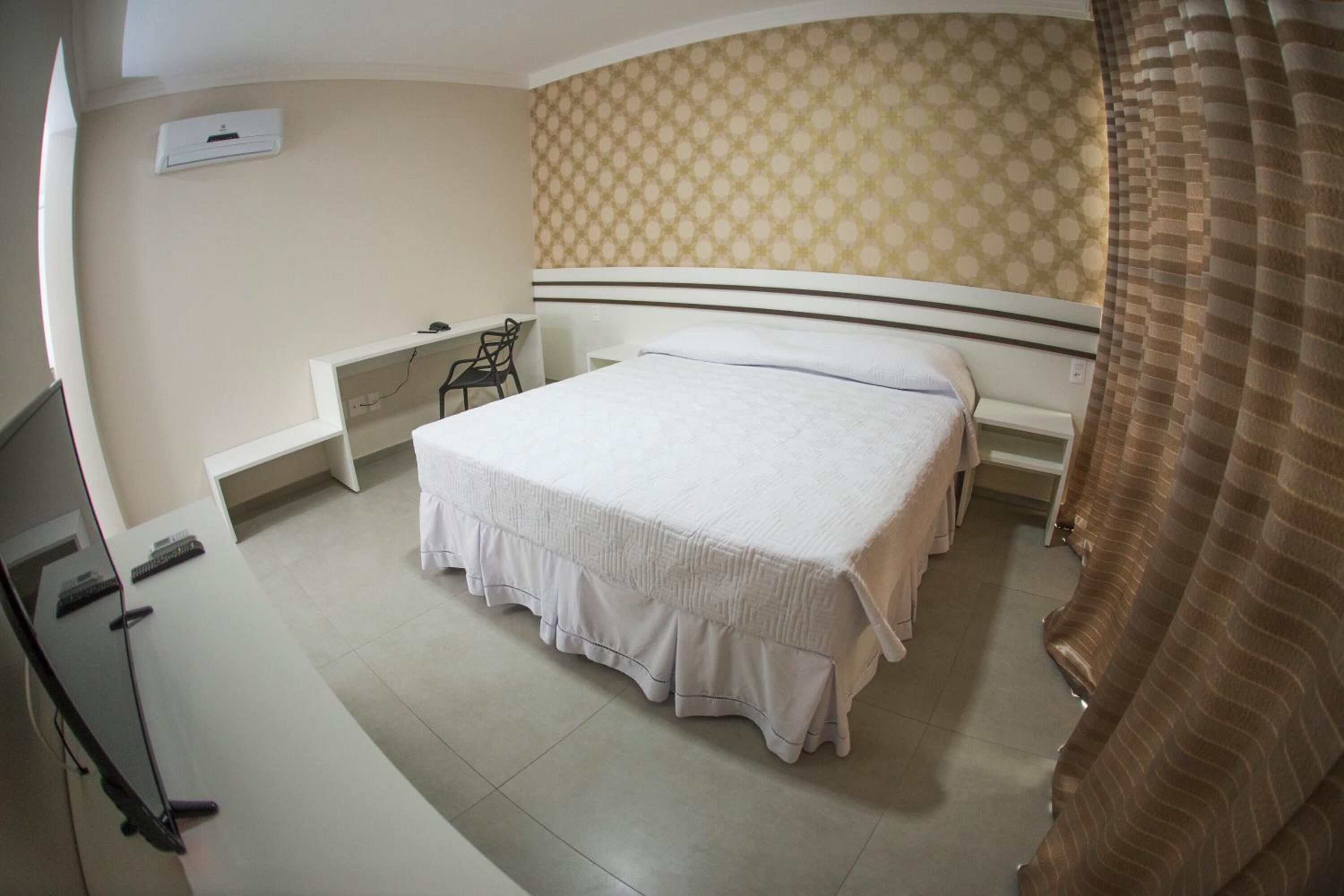 A bedroom with a bed, a desk, and a chair.