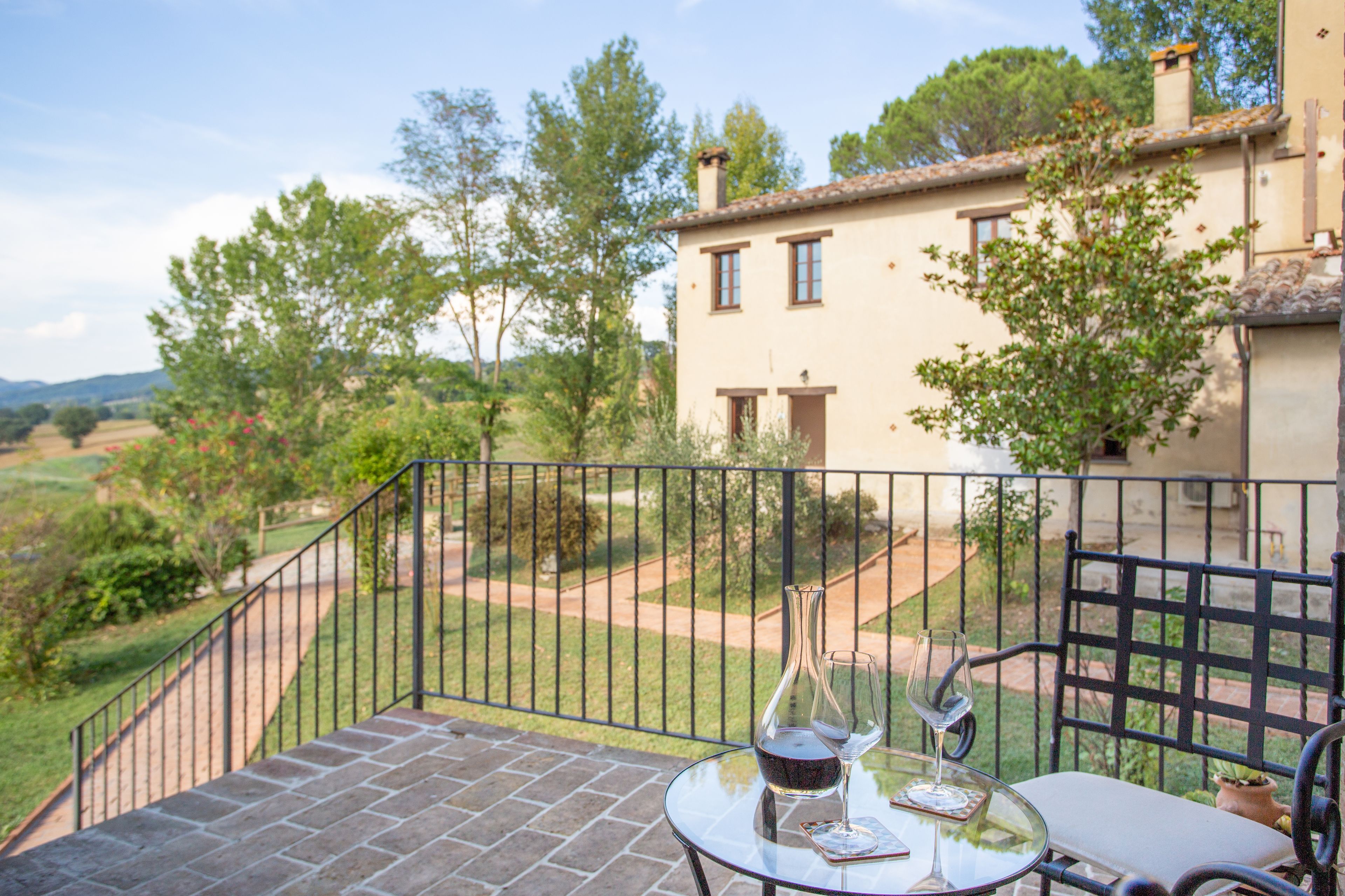 A terrace with a table and chairs, a wine glass, and a bottle.