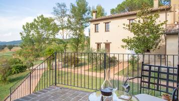 A terrace with a table and chairs, a wine glass, and a bottle.