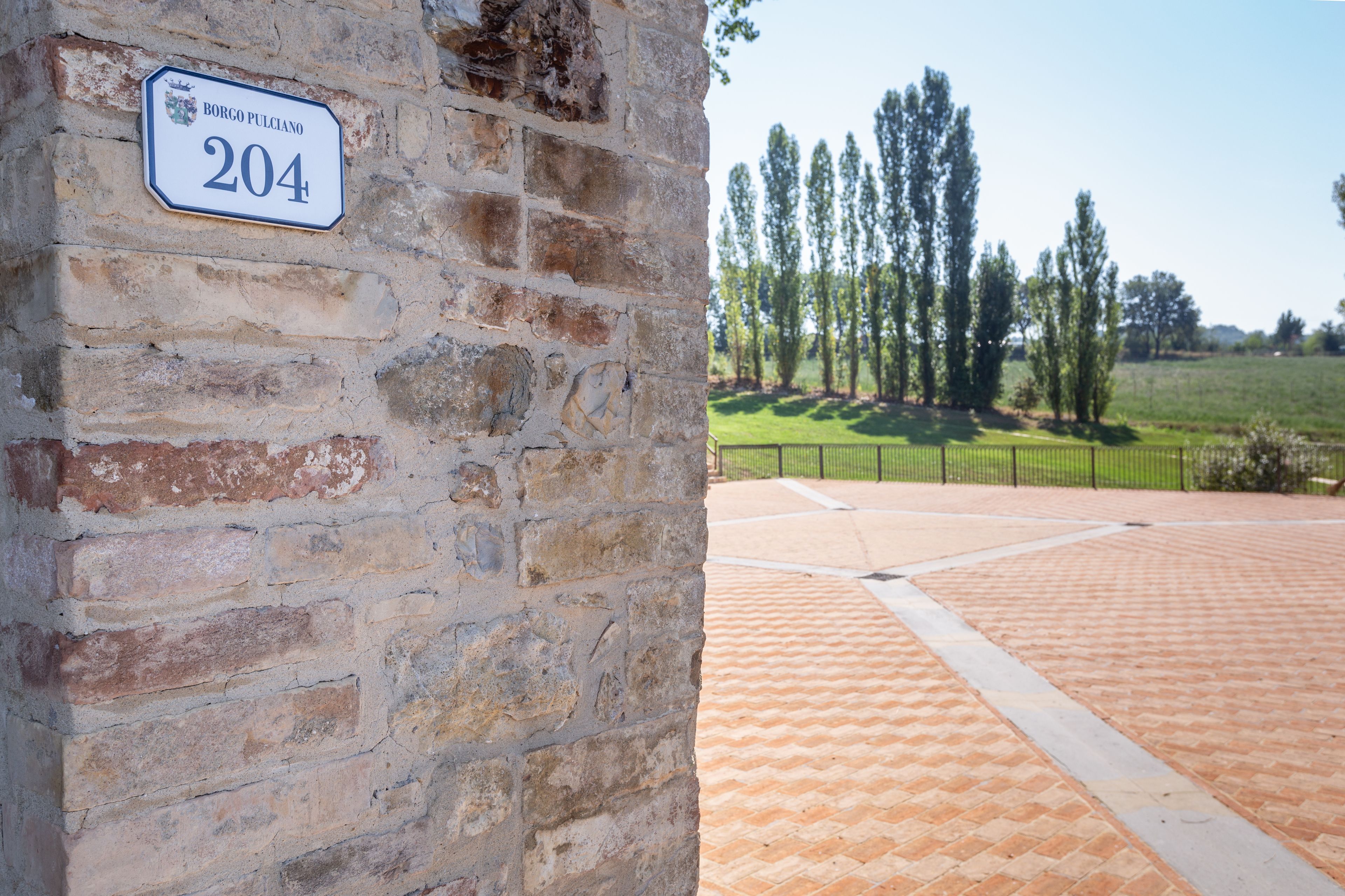 A brick wall with a house number sign.