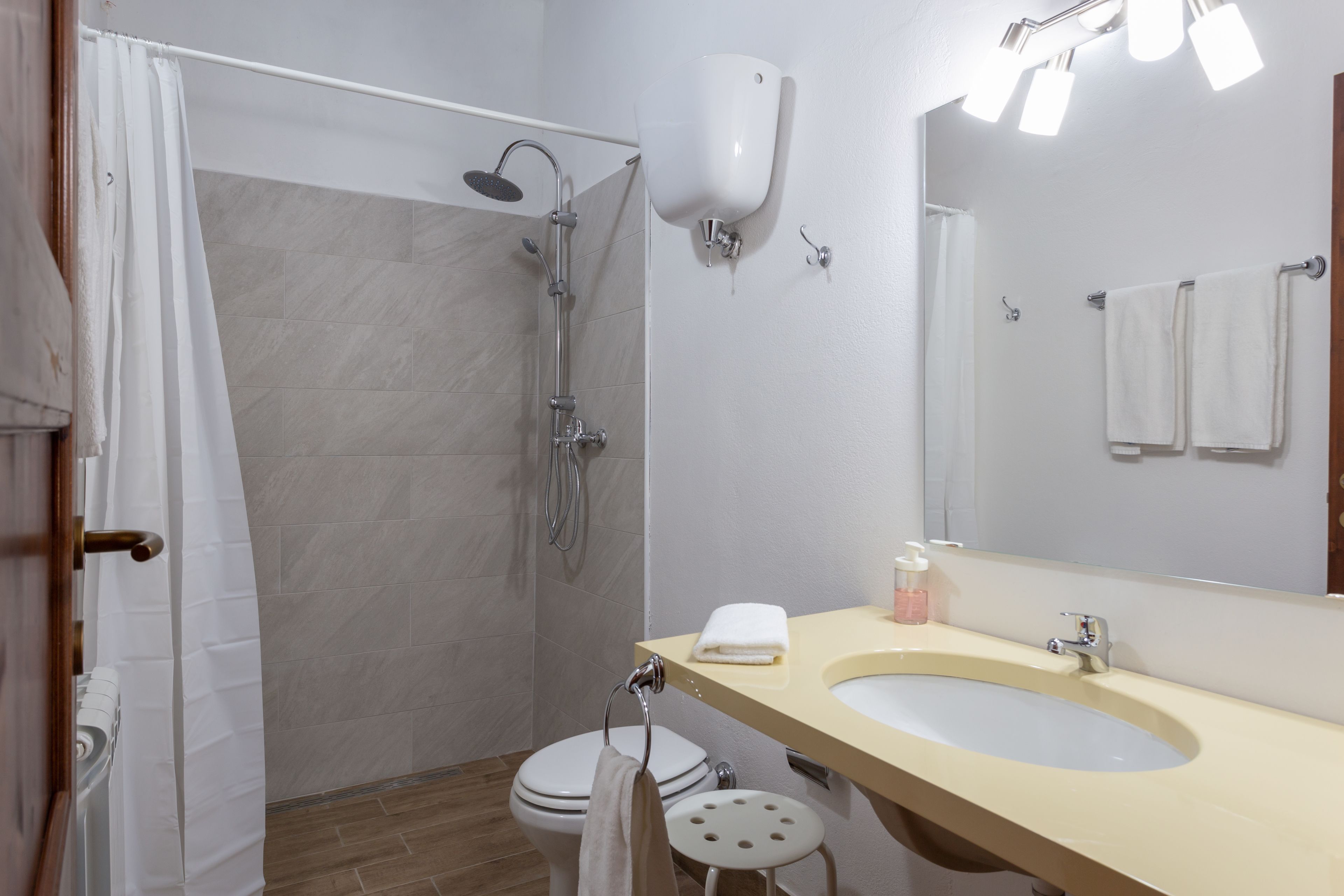 Ein Badezimmer mit Dusche, Toilette, Waschbecken und Spiegel.