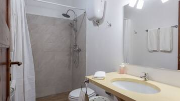 Ein Badezimmer mit Dusche, Toilette, Waschbecken und Spiegel.