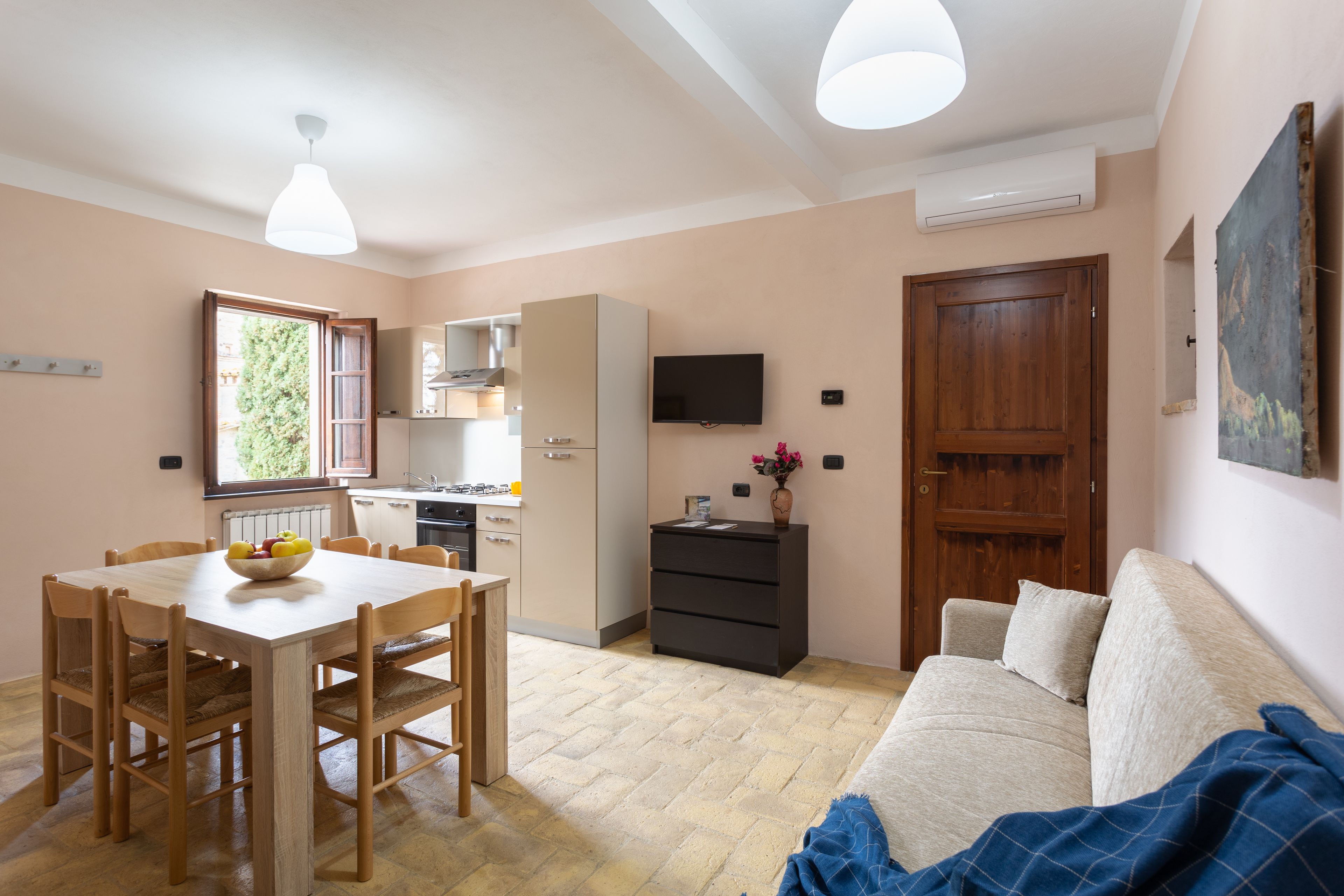Een compacte leefruimte met een eethoek, kitchenette en een bank.