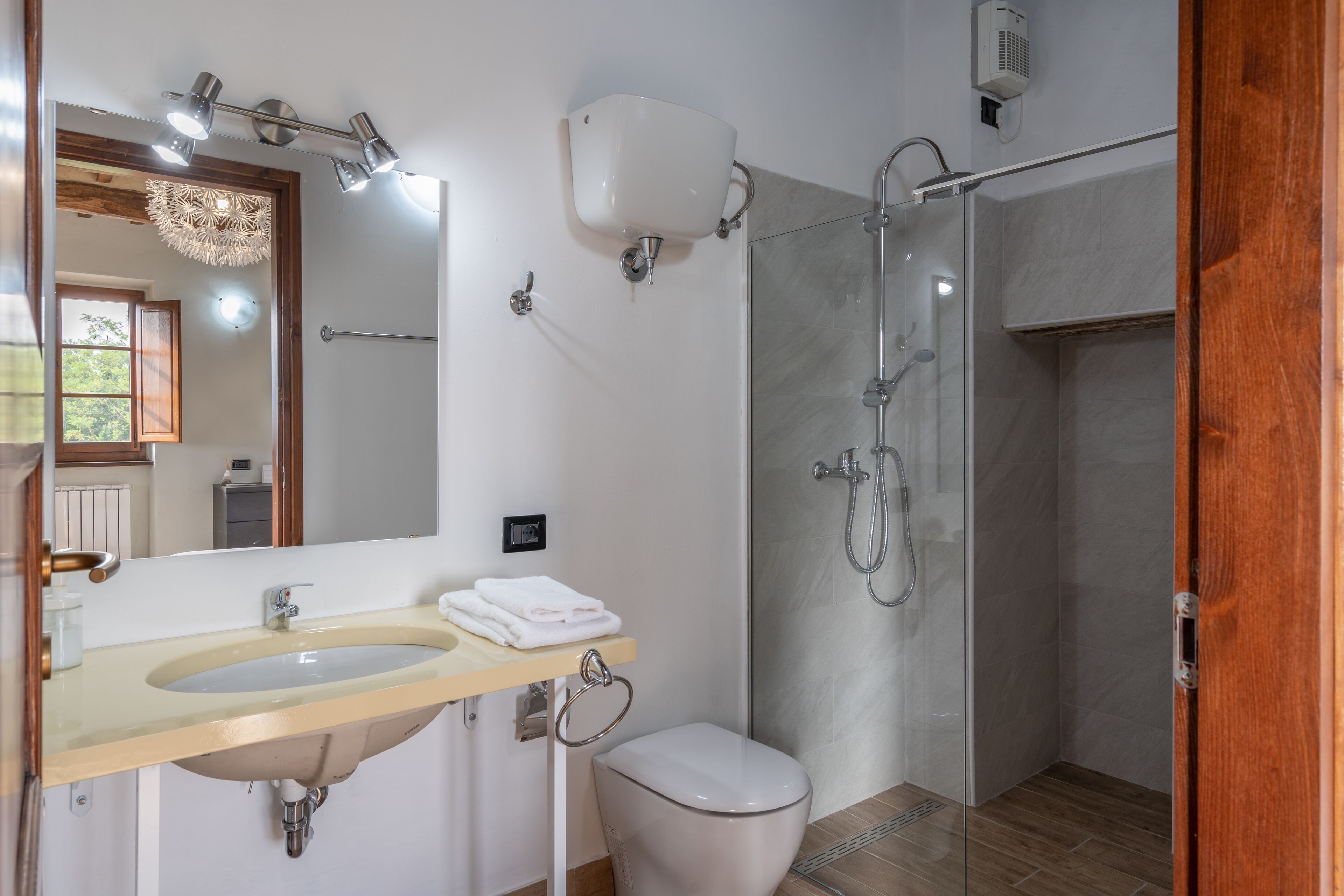 A modern bathroom with a double sink, a toilet, and a glass-enclosed shower.
