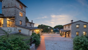 Ein Steinhaus mit einem gepflasterten Innenhof, einem Holzzaun und einem roten Weg.