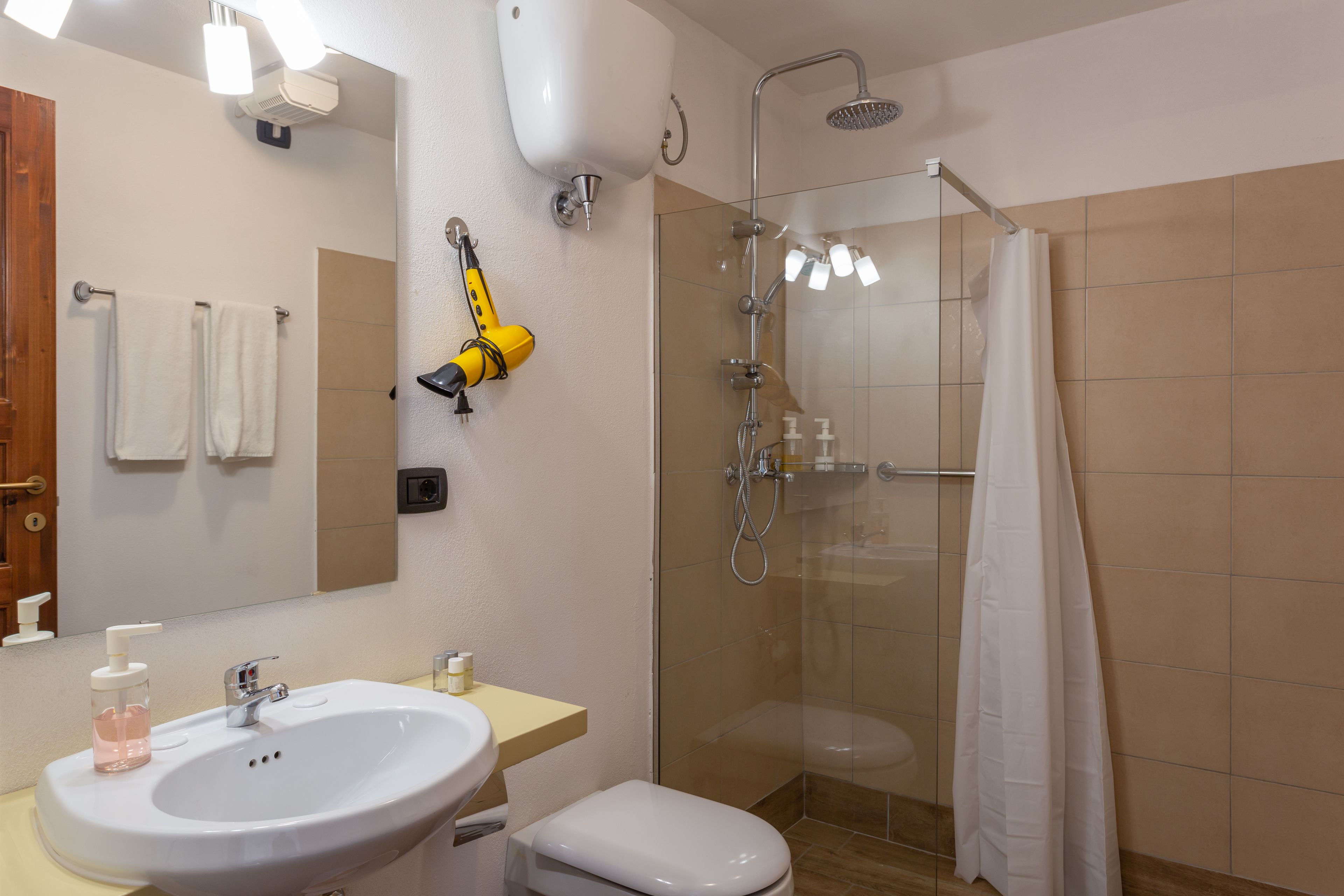 A bathroom with a sink, toilet, and a glass-enclosed shower area.