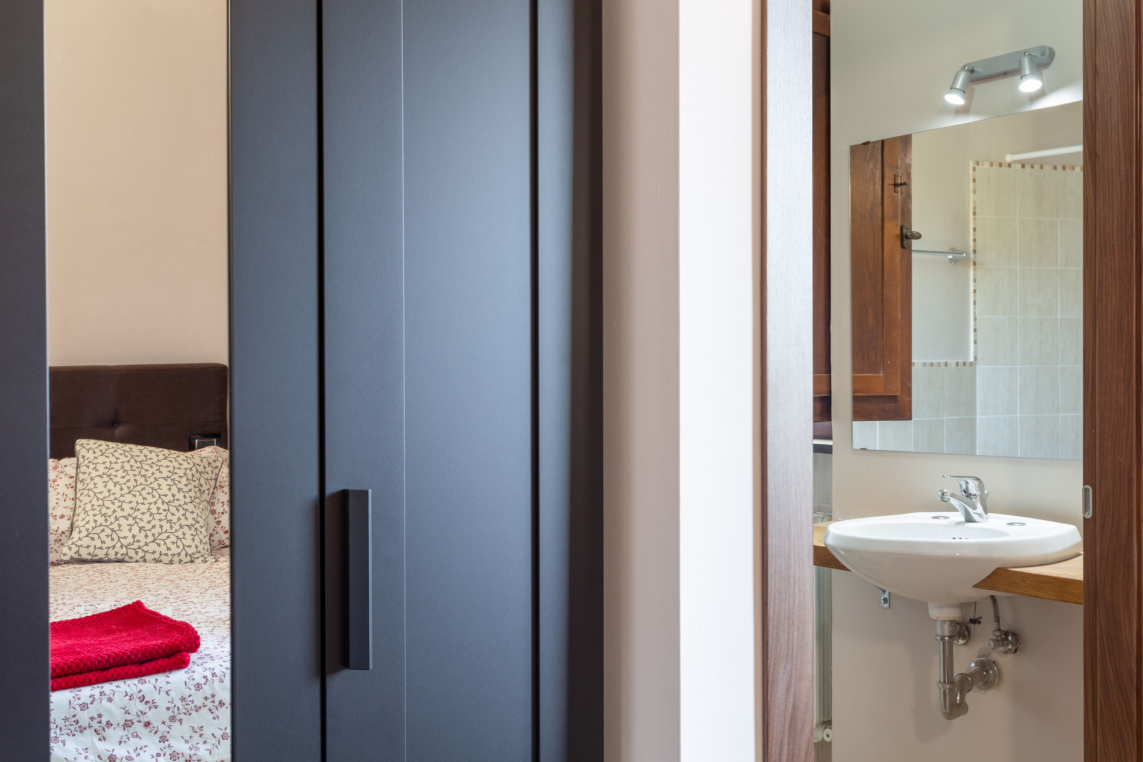 A modern bathroom with a white sink, mirror, and wooden countertop.