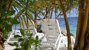 White lounge chairs on a sandy beach with a view of the ocean. - Ocean Beach Inn - Maldives (Hangnaameedhoo)