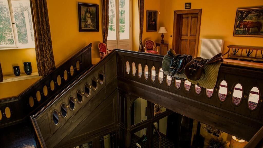 A wooden staircase with circular cutouts, a bench, and a view of a room with a door and a window.