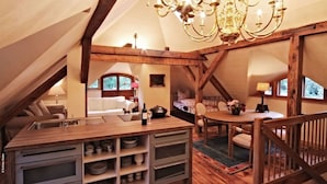A cozy attic bedroom with a wooden ceiling, a chandelier, a dining table, and a cozy seating area. - Schloss Stülpe (Nuthe-Urstromtal)