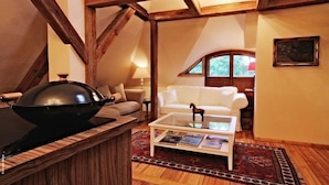 A cozy living room with a wooden ceiling, a white sofa, a glass coffee table with magazines, and a decorative bowl. - Schloss Stülpe (Nuthe-Urstromtal)