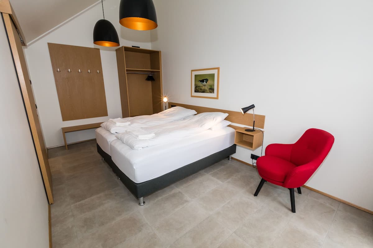 Een slaapkamer met een bed, een rode stoel, een kledingkast en een bureau.