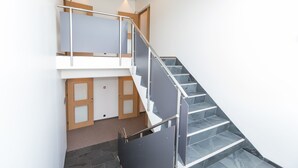 A modern staircase with glass railings and a wooden door at the bottom. - Hrímland Apartments (Akureyri)
