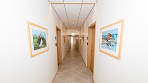 A hallway with framed pictures of birds on the walls, a tiled floor, and wooden doors. - Hrímland Apartments (Akureyri)