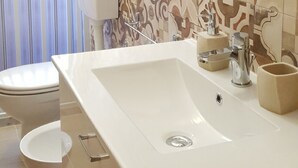 A bathroom with a large sink, a toilet, and a hairdryer mounted on the wall. - Oasi Iblea (Ragusa)