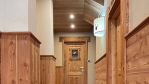 A wooden hallway with a red carpet leading to a door marked "Ski Room". - Case Vacanza Perron (Sauze d'Oulx)