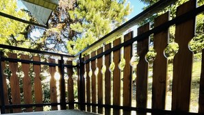 A covered outdoor patio with a stone floor and a wooden fence with decorative elements. - Case Vacanza Perron (Sauze d'Oulx)