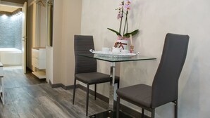A modern hotel room with a glass table set for two, a potted orchid, and a tray with a teapot and cups. - Art In B&B (Salerno)