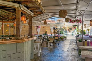 An indoor patio area with stone flooring, wooden bar counter, and seating arrangements. - Hotel Sirena Beach (Corfu)