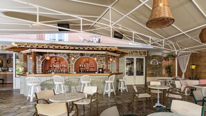 A bar area with a stone counter, white chairs, and hanging wicker lamps. - Hotel Sirena Beach (Corfu)