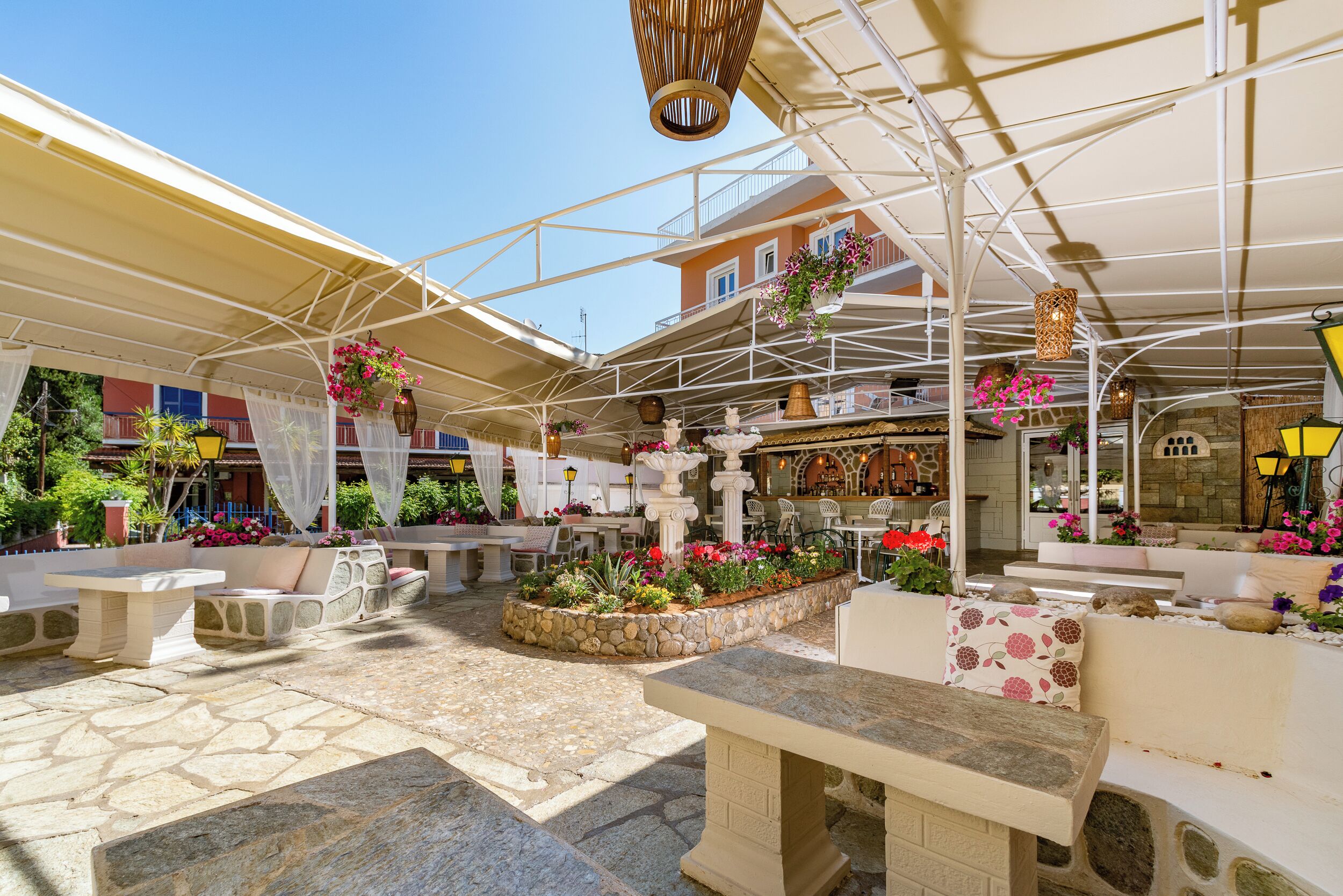 An outdoor patio area with stone flooring, seating arrangements, and hanging flower baskets.