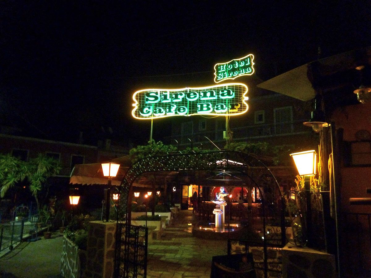 A neon sign for Sirena Cafe Bar at night.