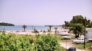 A beach with boats, palm trees, and a clear sky. - Hotel Sirena Beach (Corfu)