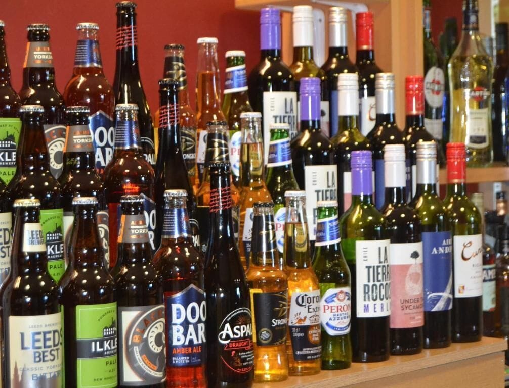 Une variété de boissons en bouteille, notamment de la bière, du vin et des spiritueux, est exposée sur des étagères.