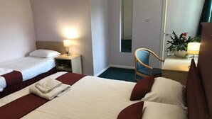 Habitación de hotel con dos camas, una silla, un escritorio y un espejo.