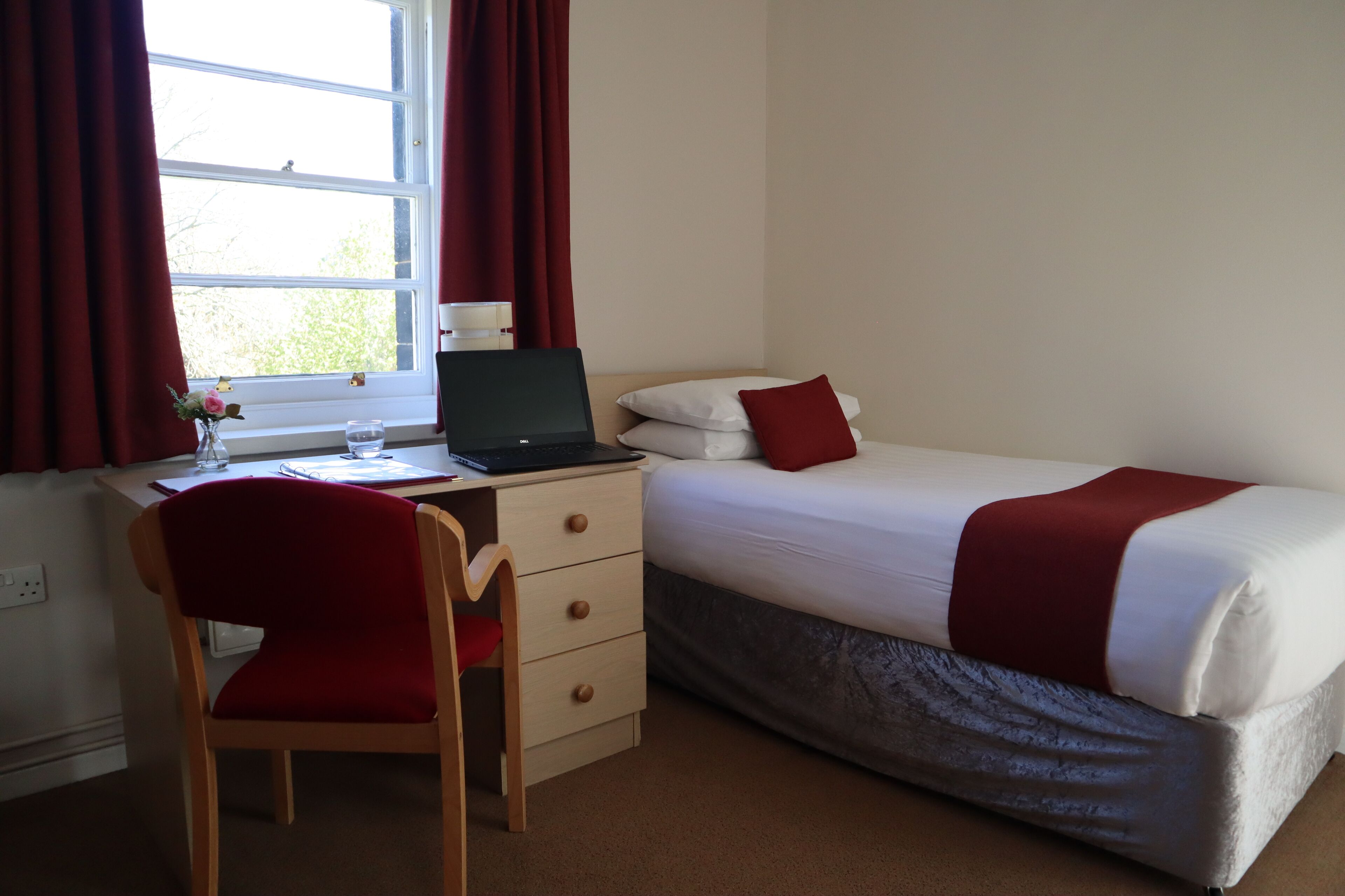 A hotel room with a desk, chair, bed, and window with curtains.