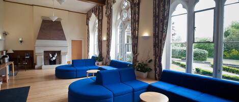 A modern living room with blue sofas, a fireplace, and large windows with decorative frames.