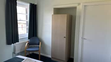 Una habitación con cama, una silla, armario y puerta.