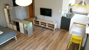 Ein modernes Wohnzimmer mit einer Couch, einem Couchtisch, einem Fernseher und einer kleinen Küchenzeile.