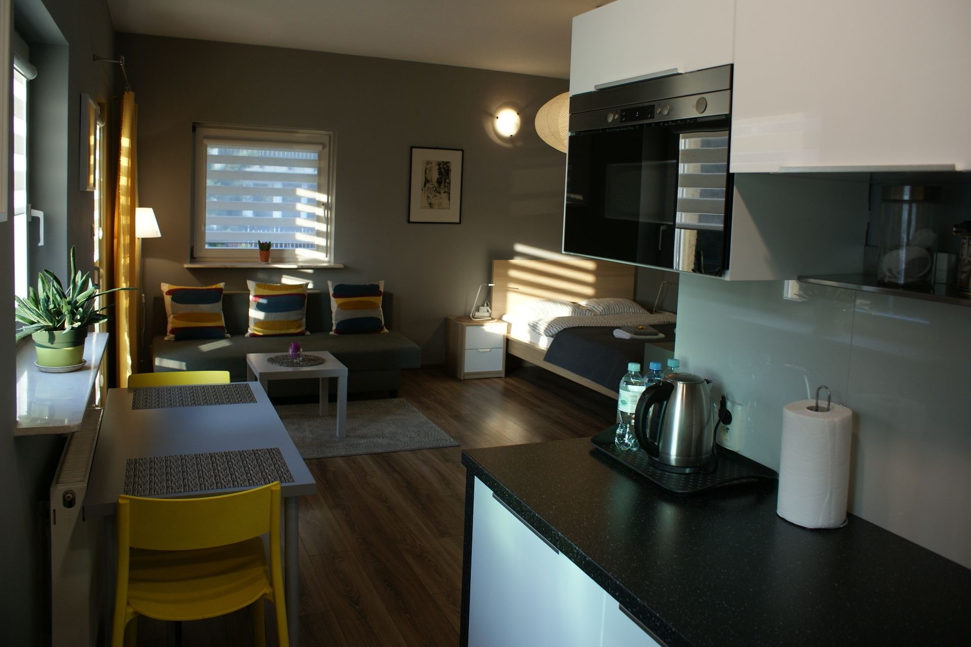Un espace de vie compact comprenant un coin cuisine, un coin repas et un lit.