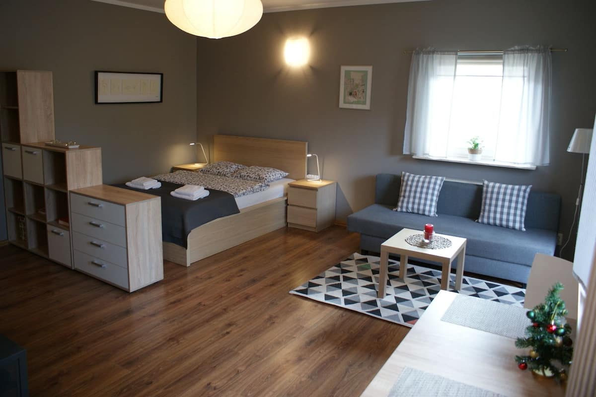 A modern bedroom with a bed, bedside tables, a sofa, and a small table.