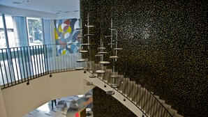 A modern interior with a staircase, glass railing, and abstract wall art. - Hotel Continental Horizonte (Luanda)