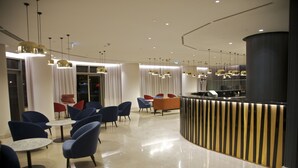 A modern lobby with round tables and blue chairs, a reception desk, and pendant lighting. - Hotel Continental Horizonte (Luanda)