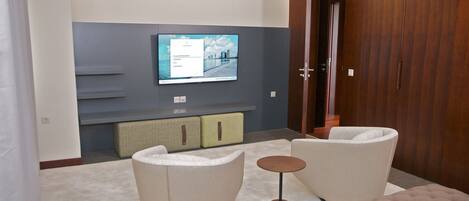 Una sala de estar moderna con una televisión de pantalla plana montada en la pared, un sofá, una mesa de centro redonda y unidades de almacenamiento empotradas.