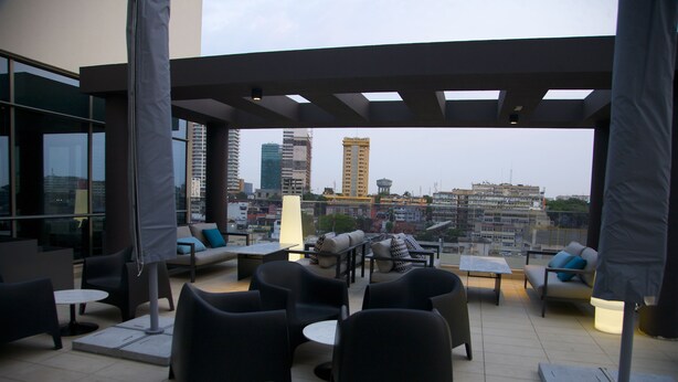 An outdoor seating area with modern furniture and a city view. - Hotel Continental Horizonte (Luanda)