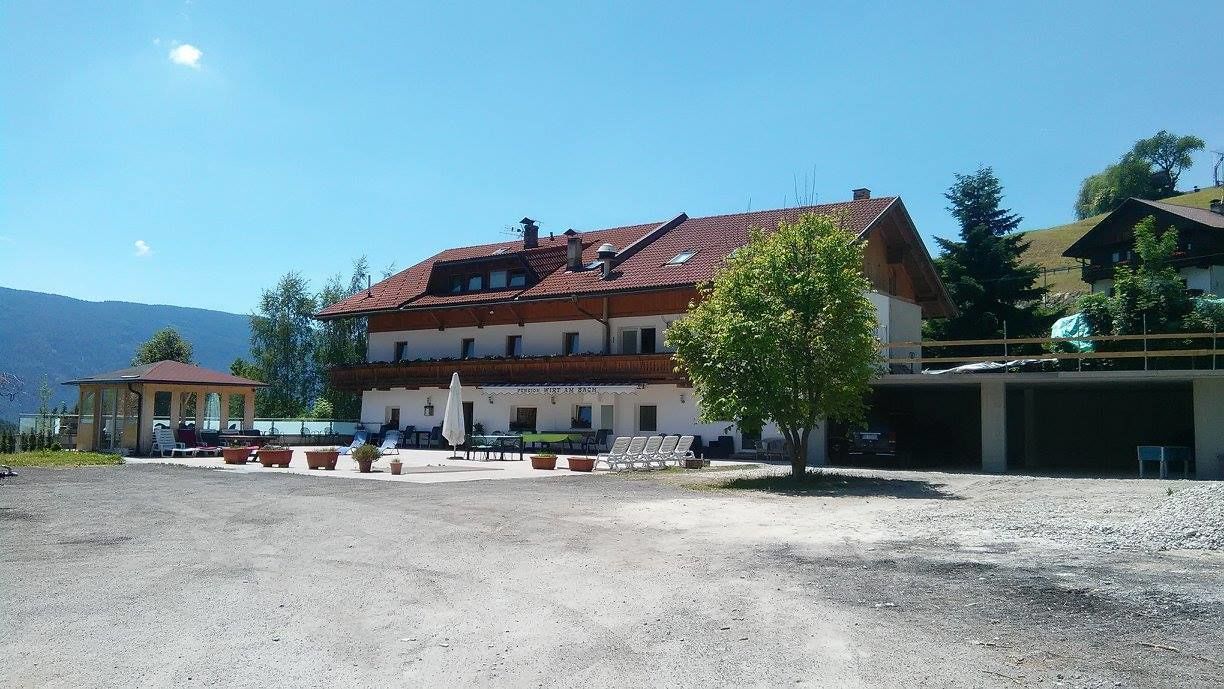 A two-story building with a red-tiled roof, a balcony, and a gravel courtyard.
