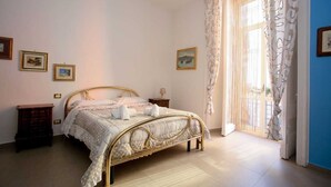 A bedroom with a bed, nightstands, and a window with curtains. - Don Carlo Rooms (Naples)
