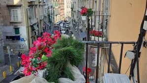 A narrow street with buildings on both sides, balconies with plants, and a clear sky. - Don Carlo Rooms (Naples)