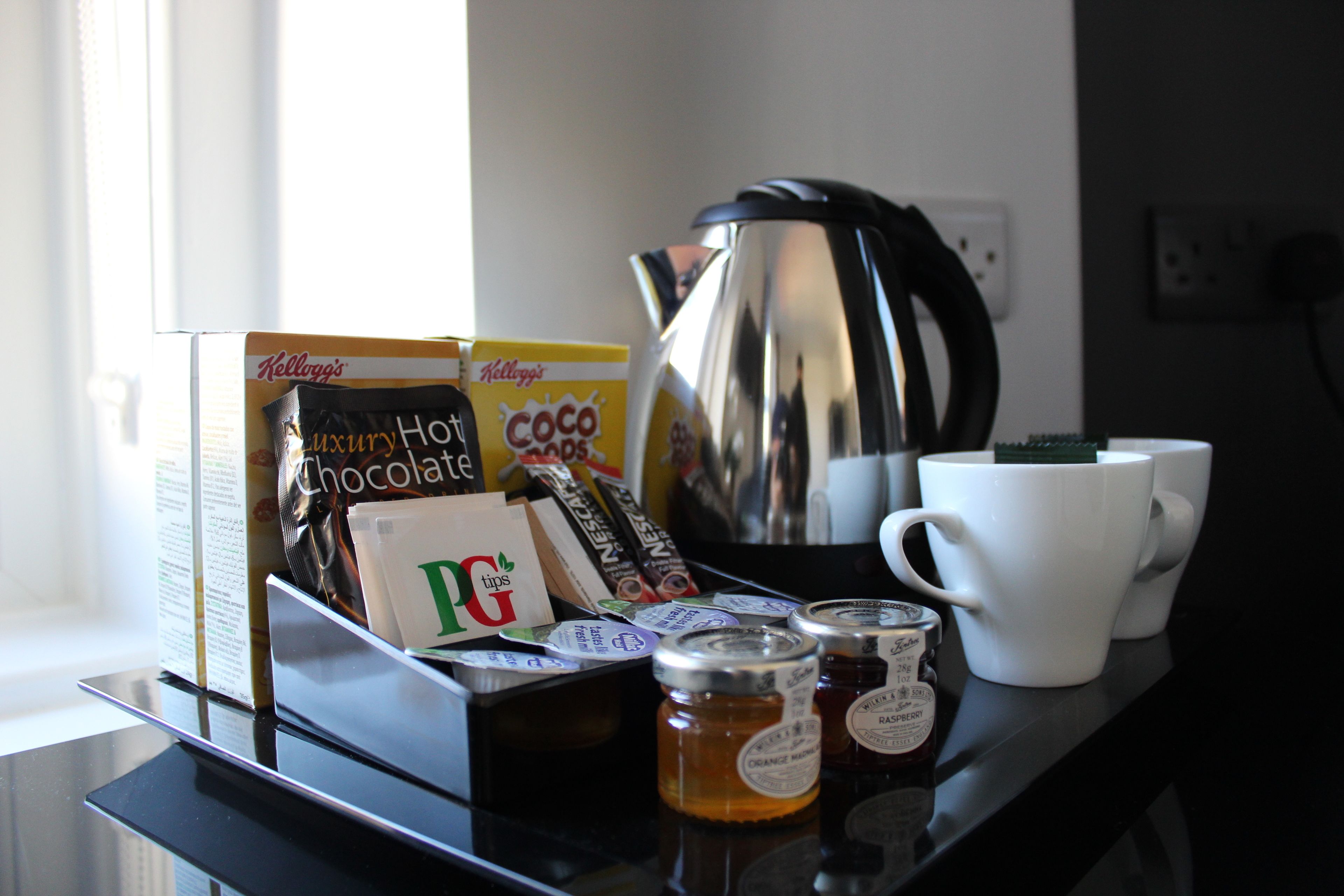 A coffee station with a coffee pot, cups, and various coffee products.
